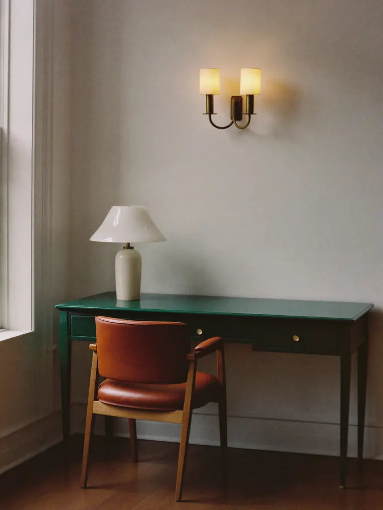 A green lacquered desk with an alabaster lamp and a leather chair
